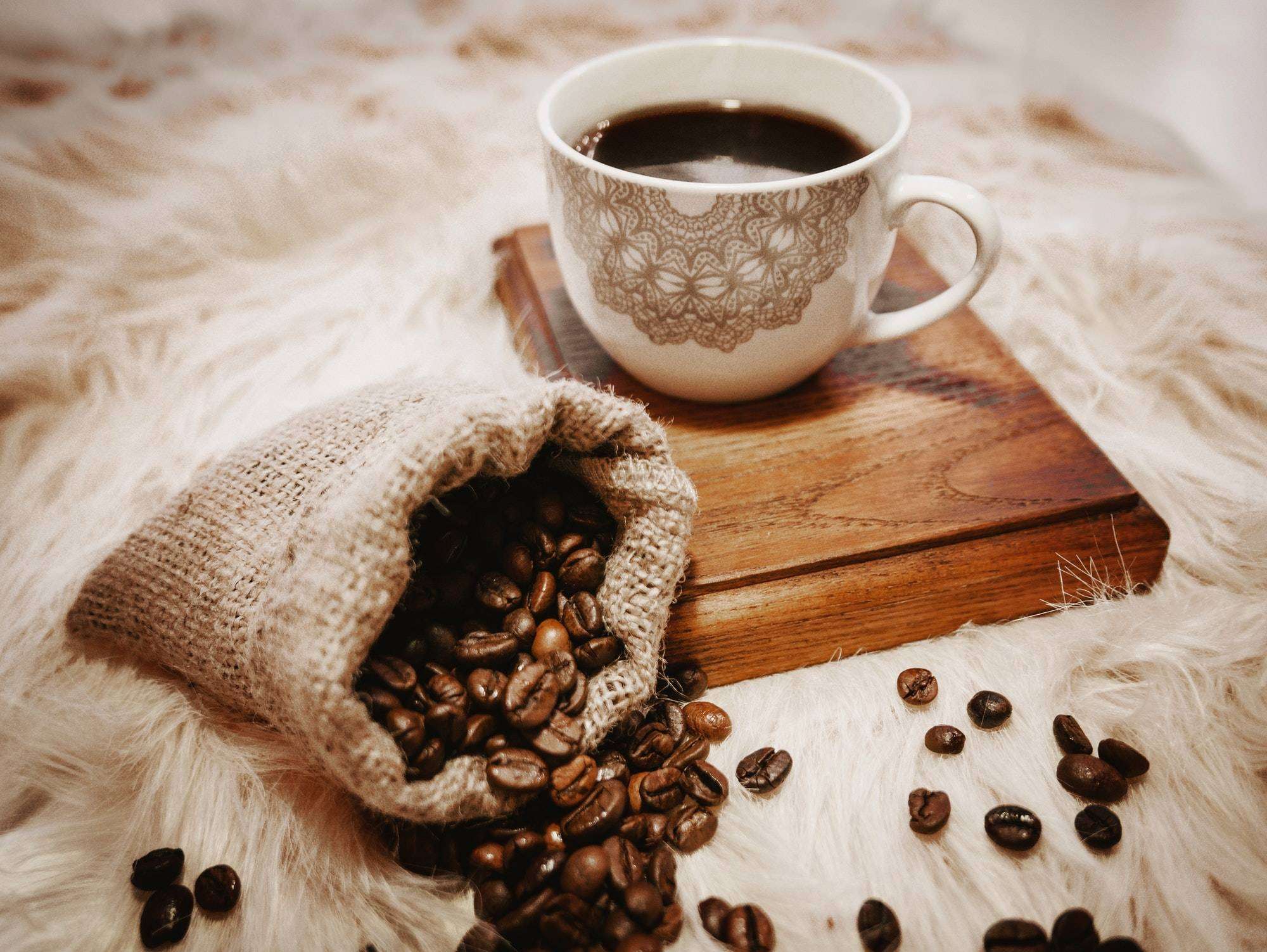Close-up image of cup of black coffee on wooden coaster.